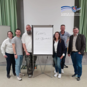 Gruppenfoto eines Netzwerktreffens: Sieben Personen stehen in einem Raum um ein Flipchart mit der Aufschrift „Kirmes ist (für mich) …“. Das Signet des Schwalm-Eder-Kreises ist im Bild eingeblendet.