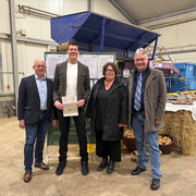 Vier Personen stehen in einer Halle vor Informationsplakaten und landwirtschaftlichen Maschinen. Eine Person in der Mitte hält ein Dokument in den Händen. Von links: Jürgen Kaufmann (Erster Kreisbeigeordneter Schwalm-Eder-Kreis), Matthias Pfetzing (Einrichtungsleiter Gut Halbersdorf), Susanne Simmler (LWV-Landesdirektorin) und Stefan Gerland (kaufmännischer Direktor Hephata Diakonie).