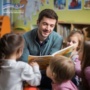 Ein Erzieher sitzt in einer Kindertagesstätte auf dem Boden und liest mehreren Kindern aus einem bunten Bilderbuch vor. Die Kinder hören aufmerksam zu und sitzen um ihn herum. Im Hintergrund sind Regale mit Büchern und bunte Kinderzeichnungen an der Wand zu sehen. Oben links ist das Logo des Schwalm-Eder-Kreises mit dem Schriftzug „Der Kreis mit den schönsten Ecken“ eingeblendet.