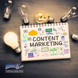 Auf einem Tisch liegt ein Notizblock mit der großen Aufschrift „Content Marketing“. Rundherum sind mehrere Glühbirnen platziert, eine davon leuchtet. Auf dem Notizblock sind bunte Skizzen und Symbole zu Themen wie Online-Werbung, Social Media, Technik, Zielgruppen und Strategie zu sehen. Unten links ist das Logo des Schwalm-Eder-Kreises mit dem Schriftzug „Der Kreis mit den schönsten Ecken“ eingeblendet.