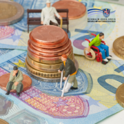 Auf dem Bild liegen verschiedene Euro-Geldscheine und Münzen, auf denen kleine Figuren platziert sind. Die Figuren stellen Menschen mit unterschiedlichen Lebenslagen dar – zum Beispiel eine Person im Rollstuhl, eine ältere Person mit Gehhilfen und eine sitzende Person. In der Bildmitte befindet sich ein gestapelter Münzturm. Oben rechts ist das Logo des Schwalm-Eder-Kreises zu sehen.