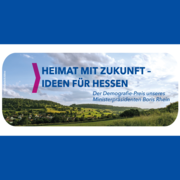 Die Grafik trägt den Titel „Heimat mit Zukunft – Ideen für Hessen“ und verweist auf den Demografie-Preis des hessischen Ministerpräsidenten Boris Rhein. Im Hintergrund ist eine weite, grüne Hügellandschaft mit Feldern, Bäumen und einem Dorf unter bewölktem Himmel zu sehen. Das Design ist in Blau gehalten und enthält einen pinken Pfeil als grafisches Element.