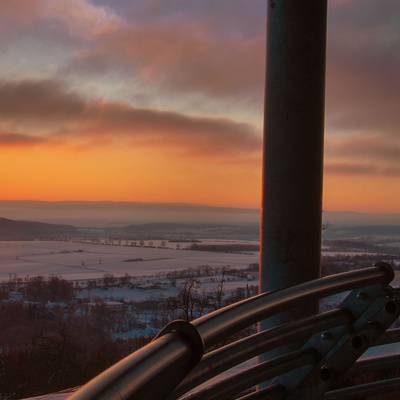 Sonnenaufgang über der winterlichen Landschaft am Aussichtspunkt der Ruine Löwenstein mit Blick über Täler und Felder.