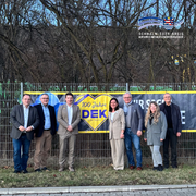 Gruppenfoto von sieben Personen vor einem Bauzaun mit Banner „100 Jahre EDEKA in der Region“. Die Personen stehen nebeneinander im Freien vor kahlen Bäumen. Von links nach rechts: Landrat Winfried Becker, Dr. Rainer Waldschmidt (Hessen Trade & Invest GmbH), Florian Kramm (EDEKA Handelsgesellschaft Hessenring mbH), Tatjana Grau-Becker (Leiterin Wirtschaftsförderung Schwalm-Eder-Kreis), Michael Hanke (Bürgermeister Malsfeld), Renate Richter (Wirtschaftsförderung) und Klaus Stiegel (Geschäftsführer Zweckverband Gewerbegebiet Mittleres-Fuldatal). Oben rechts ist das Logo des Schwalm-Eder-Kreises zu sehen.