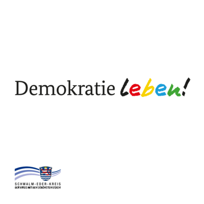 Auf weißem Hintergrund steht mittig der Schriftzug „Demokratie leben!“: „Demokratie“ ist schwarz gesetzt, „leben!“ wirkt wie handgemalt und ist mehrfarbig (schwarz, rot, gelb, blau, grün) mit schwarzem Ausrufezeichen. Unten links befindet sich das Logo des Schwalm-Eder-Kreises mit Wellenlinien und Wappen sowie der Text „SCHWALM-EDER-KREIS – DER KREIS MIT DEN SCHÖNSTEN ECKEN“.