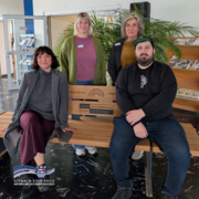 Auf dem Bild sind vier Personen (v. li.) Elena Padva (Sara-Nussbaum-Zentrum), Lena Manchen (RFES), Steffi Hoffmann (BDP) und Joel Willing (Liberale jüdische Gemeinde Nordhessen) zu sehen, die in einem Eingangsbereich auf einer Holzbank sitzen und stehen. Zwei Personen sitzen vorne auf der Bank, zwei stehen dahinter. Auf der Bank ist eine Plakette mit der Aufschrift „Schule ohne Rassismus – Schule mit Courage“ sowie „Reichspräsident-Friedrich-Ebert-Schule“ zu erkennen. Im Hintergrund stehen grüne Pflanzen und Regale mit Broschüren. Das Logo des Schwalm-Eder-Kreises befindet sich unten links im Bild.